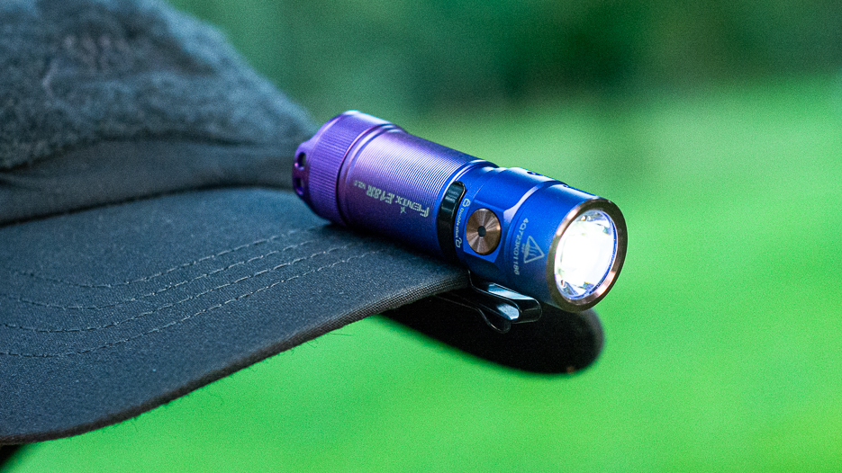 Fenix E18R V2.0 clipped to the brim of a cap.